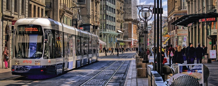 Photograph taken in Geneva, Switzerland Downtown. In the picture a surface train and several people on a normal day of work.