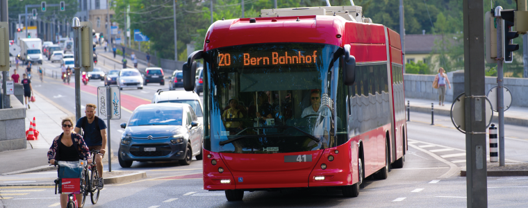 sw3_featured Lorraine Bridge with red trolley bus line 20 and cyclists at City of Bern, capital of Switzerland, on a blue cloudy summer day. Photo taken June 16th, 2022, Bern, Switzerland.