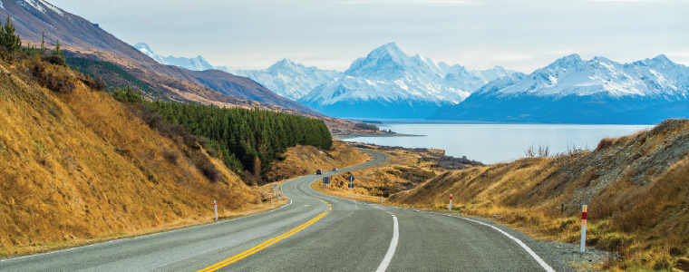 Scenic road trip of Mt Cook or Aoraki over winding road with motorhome driving and Lake Pukaki on sunny day at Peters lookout, New Zealand